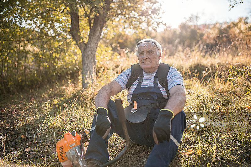 一位退休老人正坐在院子里的草地上图片素材