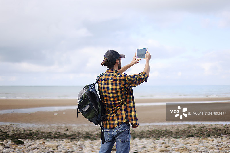 一个年轻人在海边徒步旅行时拍照图片素材