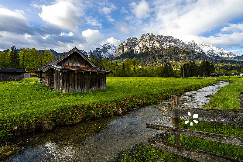在一个巴伐利亚小屋，河流和Zugspitze前面的篱笆图片素材