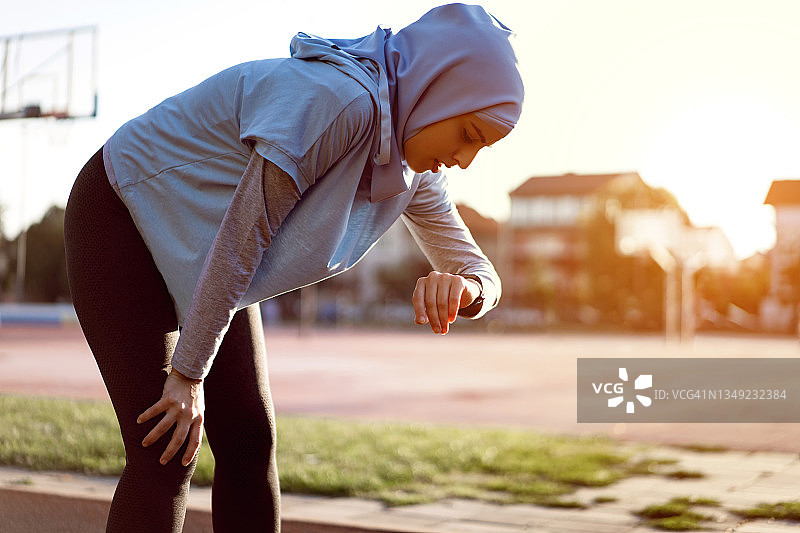 精疲力竭的穆斯林田径运动员在健身追踪器上测量她的脉搏图片素材