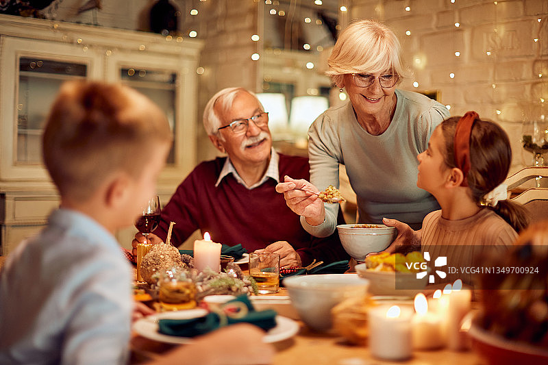 一位快乐的老妇人在感恩节餐桌上为家人上菜。图片素材