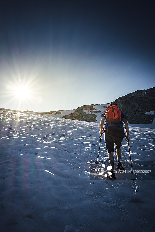 一名步行者朝着太阳跑上覆盖着积雪的冰川图片素材