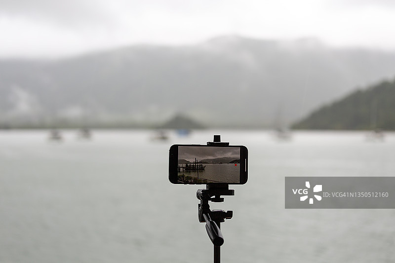 白沙湾(高张岛)-雨云，山，雨林和渔村)-三脚架上的手机相机。图片素材
