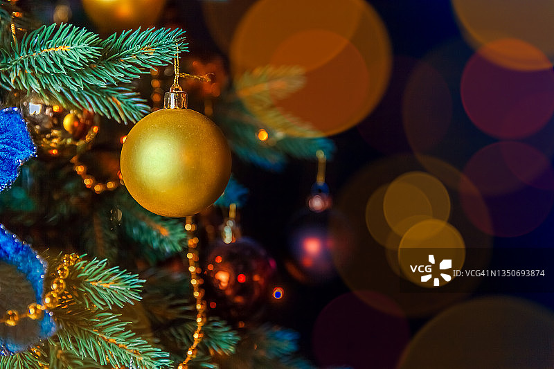经典的圣诞装饰新年树。圣诞树上装饰着金色的装饰物。经典风格设计杉木枝干散焦灯光，抽象暗背景。平安夜在家图片素材