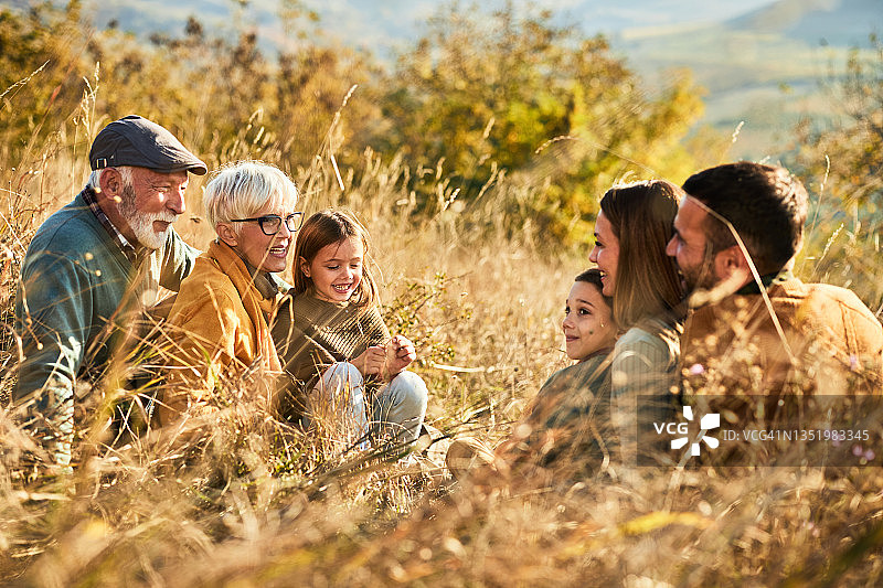幸福的大家庭在秋日的小山上聊天。图片素材