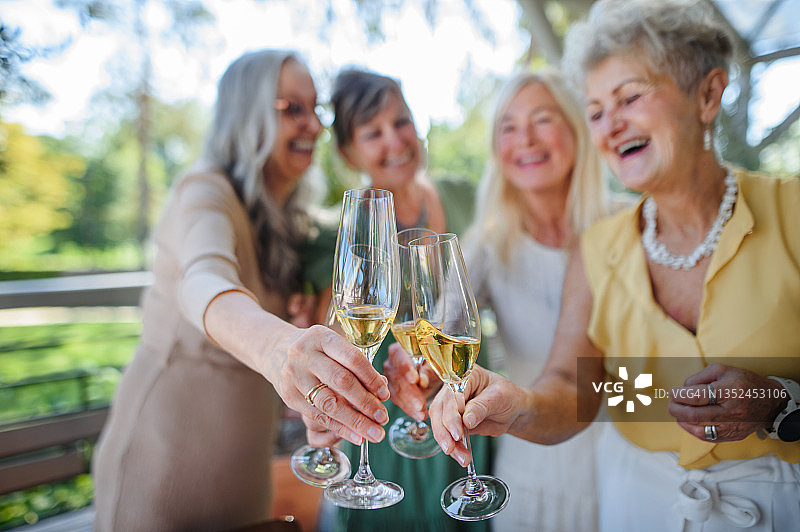 年长的女性朋友在酒店露台上庆祝祝酒。图片素材