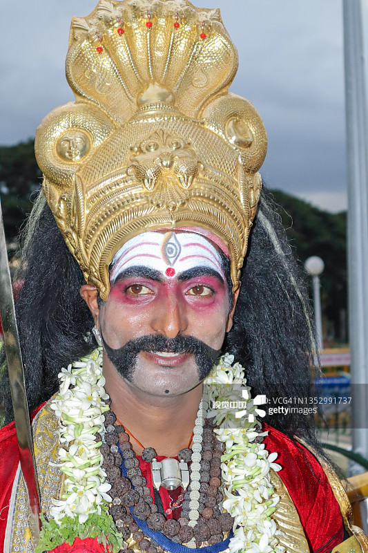 印度迈索尔宫，一名宗教民俗艺术家的肖像抓拍照片，他化着脸谱，穿着五颜六色的服装，参加杜塞赫拉节。图片素材