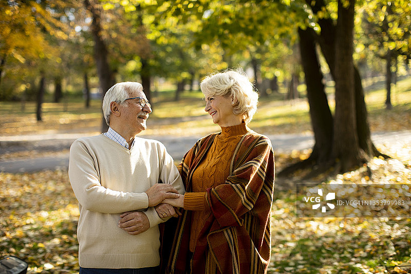 老夫妇在秋天的公园里拥抱图片素材