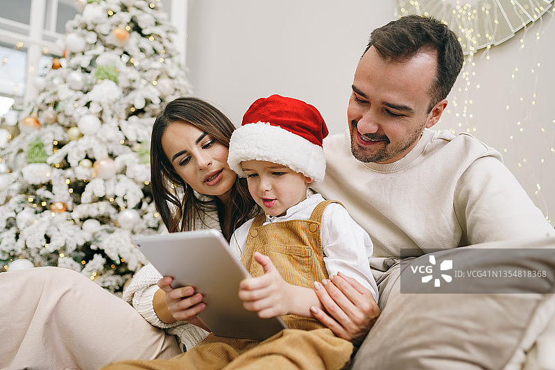 圣诞节快乐的家庭在床上玩平板电脑图片素材