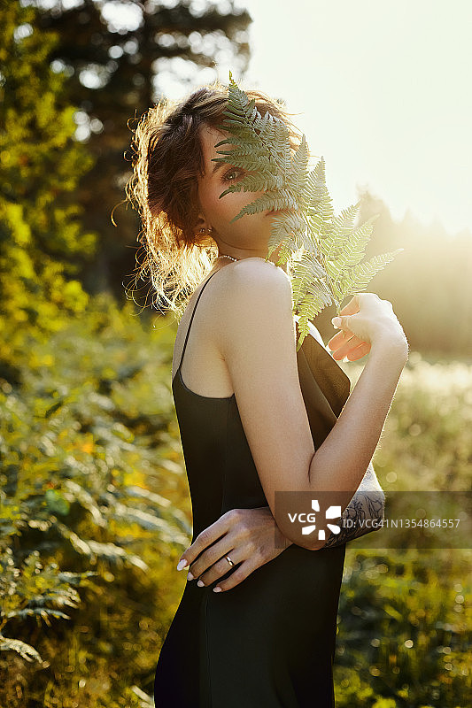 画像美丽的女人在森林在日落。女人在自然中休息，是阳光下的一幅艺术肖像图片素材