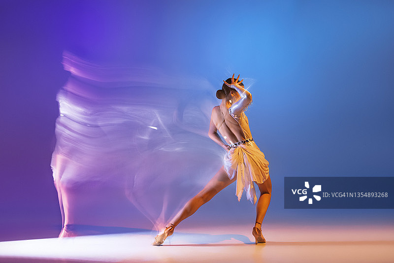 肖像的年轻优雅灵活的女人跳舞交际舞没有伙伴孤立的梯度蓝色紫色背景在霓虹灯混合光图片素材