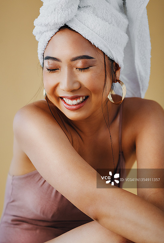 一个迷人的年轻女子独自坐着，头发用毛巾裹着图片素材