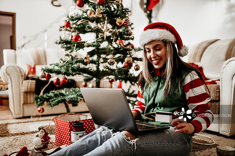 带着信用卡在圣诞树下用笔记本电脑在线购物时间图片素材