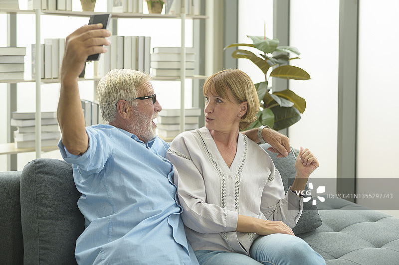 快乐的白种人老人是老人给家人或朋友视频电话，在家里放松，微笑健康的退休老人的祖父母，老年祖父母的技术概念图片素材