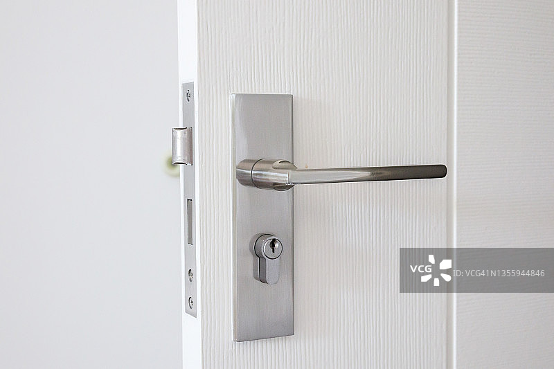 白色门上有钥匙孔的现代门把手图片素材