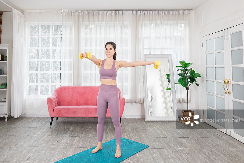 在大流行感染期间，妇女在家中客厅锻炼。图片素材