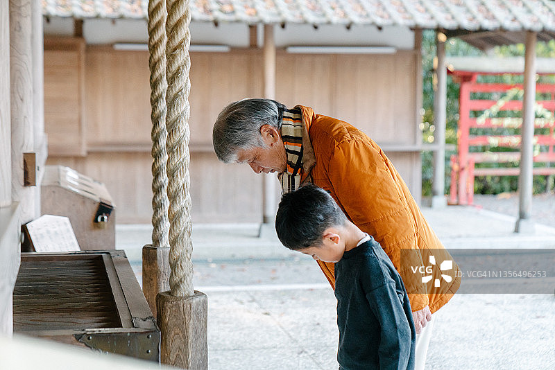 一个小男孩和他的祖父在日本寺庙祈祷图片素材