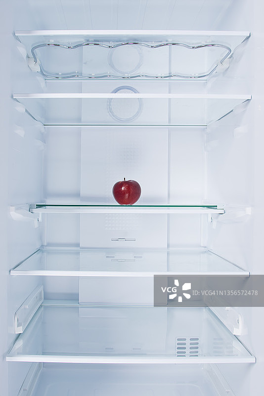 红苹果，在冰箱里，在玻璃架子上，在白色背景上图片素材