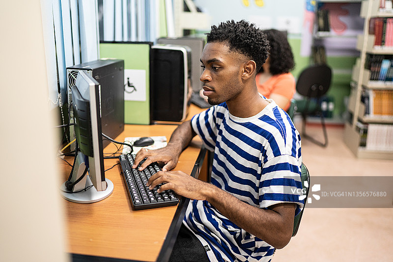 一个年轻人在图书馆里使用电脑图片素材