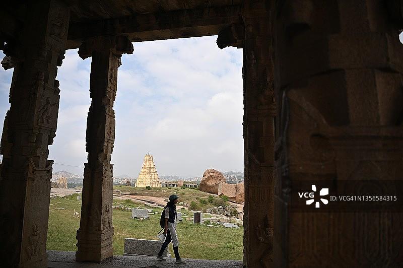 在卡纳塔克邦的汉比，一名妇女正走过一座古代寺庙的废墟图片素材