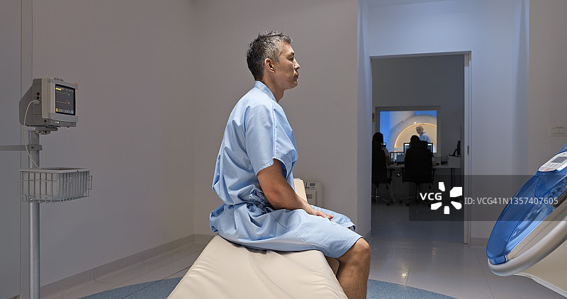 一个成熟的男人坐在核磁共振扫描仪的桌子上图片素材