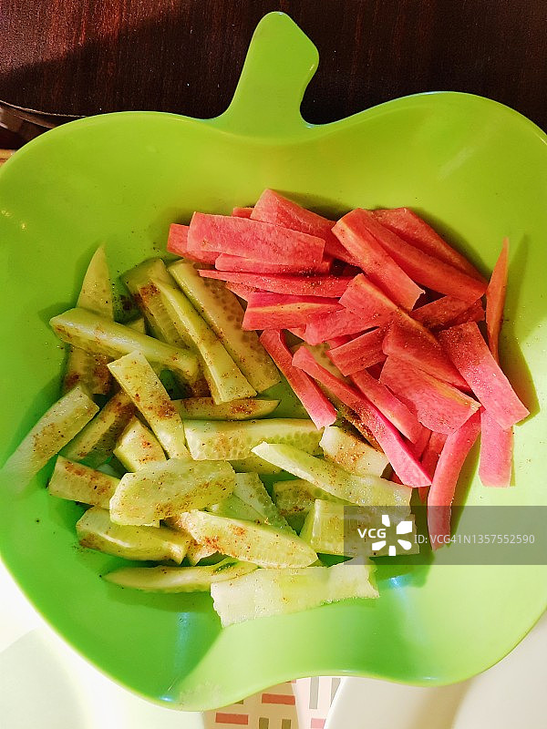胡萝卜和黄瓜切碎的沙拉条，撒上香料(马沙拉)在一个青苹果形状的碗里。图片素材