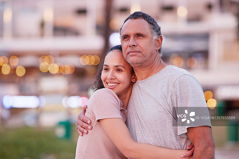 一个漂亮的年轻女子和她的父亲站在海滩上看日落图片素材