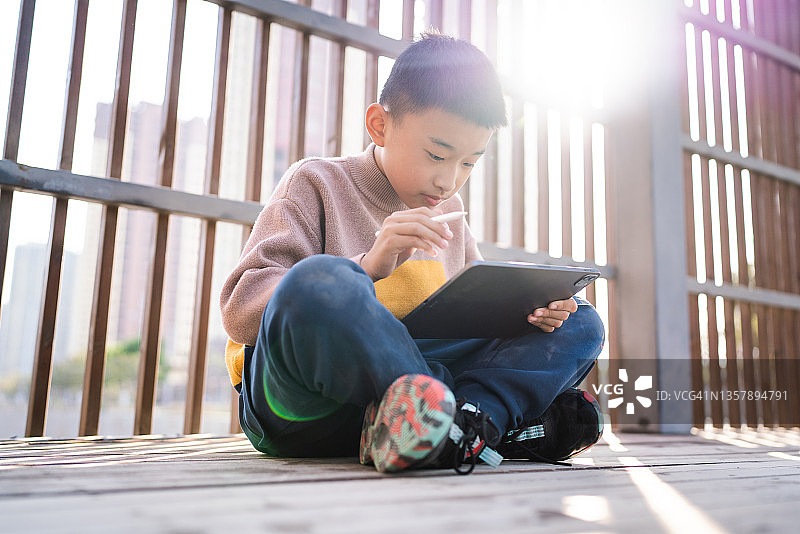 一个小男孩用iPad在草地上画画图片素材