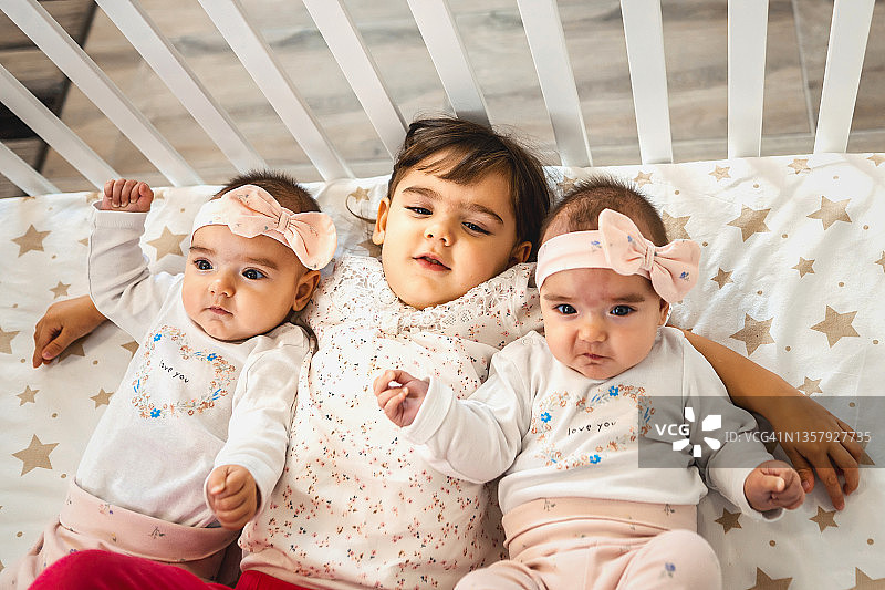 三个小妹妹在婴儿床里放松图片素材