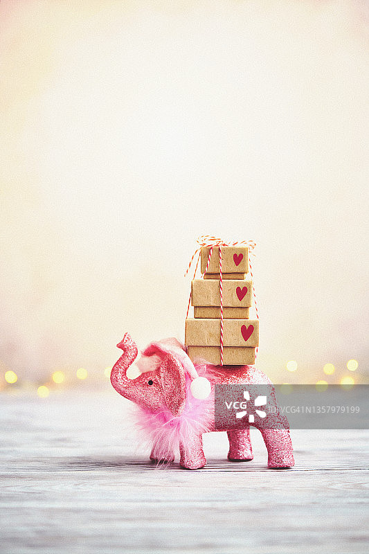 可爱的圣诞背景与闪闪发光的粉红色大象扛着一堆圣诞礼物图片素材