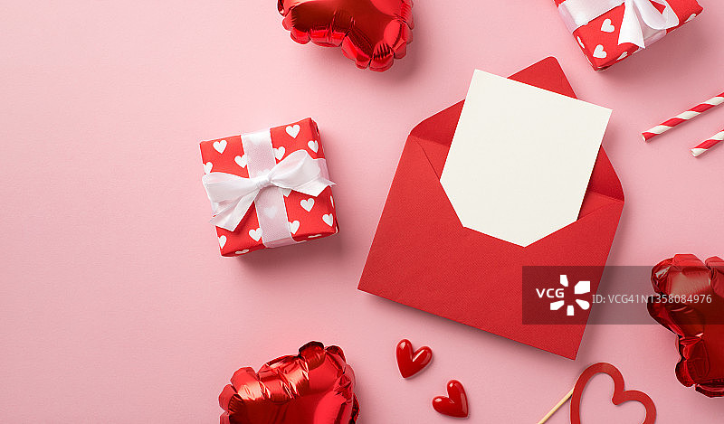 情人节装饰的顶视图照片，红色信封卡礼盒在红色包装纸与图案的心和心形气球在孤立的粉彩背景与copyspace图片素材