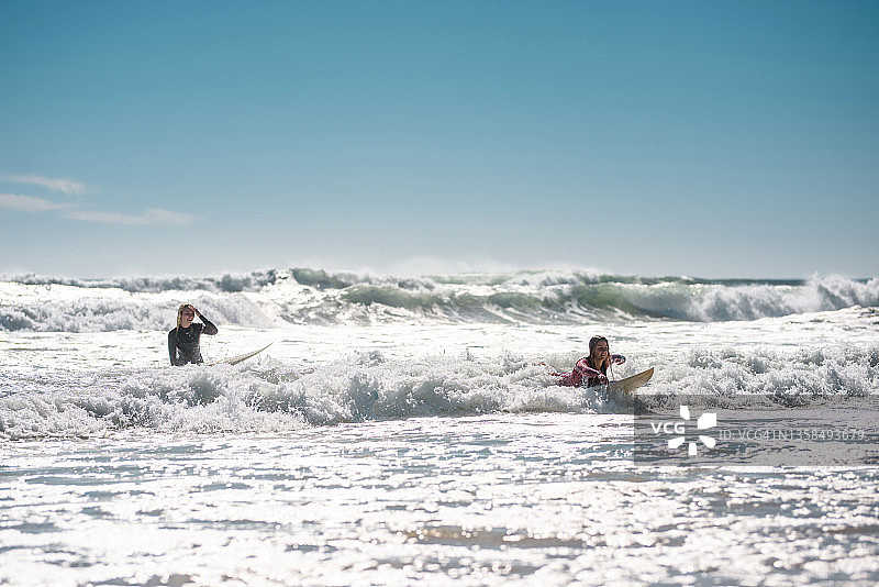 黄金海岸女性冲浪朋友骑波浪进入海岸图片素材