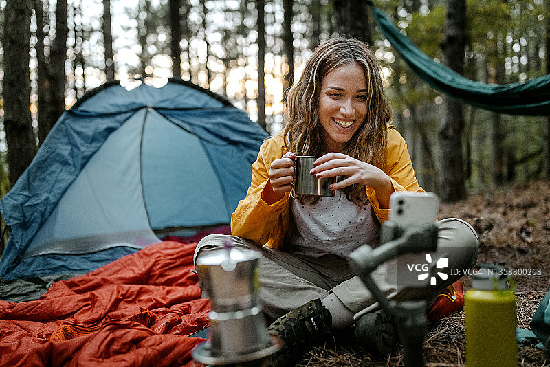 微笑的女人边喝咖啡边玩智能手机图片素材