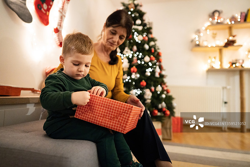 蹒跚学步的小男孩，和他的白人祖母一起打开圣诞礼物图片素材