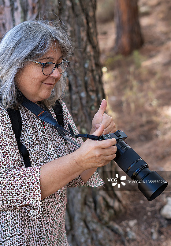 白发苍苍的老妇人在森林里拍照图片素材