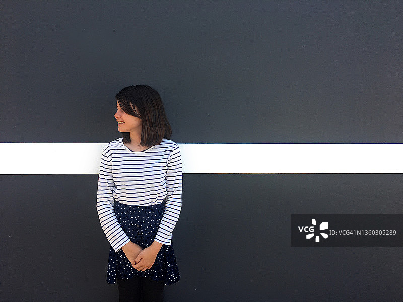 快乐的少女站在灰墙的白线图片素材