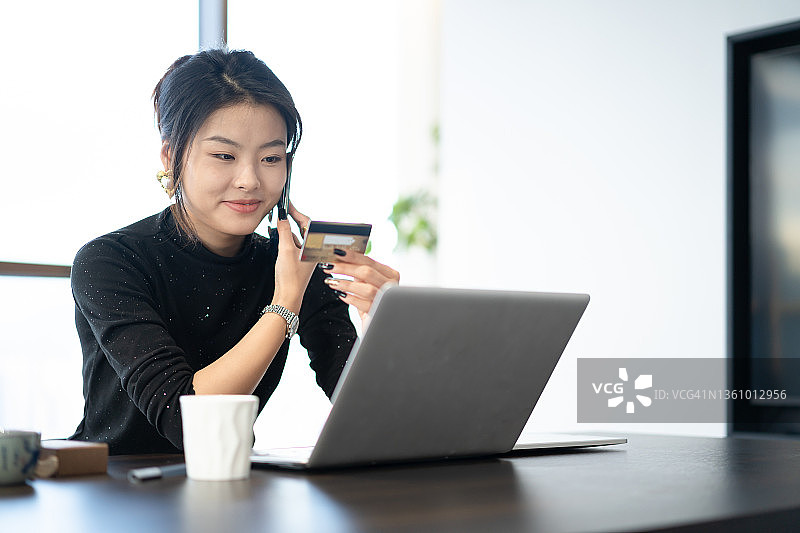 办公室里一位年轻的亚洲女性正在用电脑开视频会议图片素材