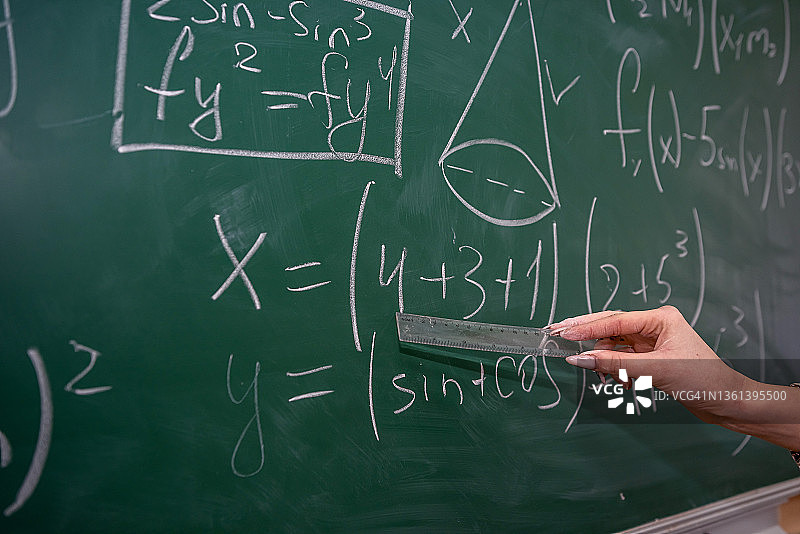 漂亮的女老师在教室里靠黑板学数学图片素材