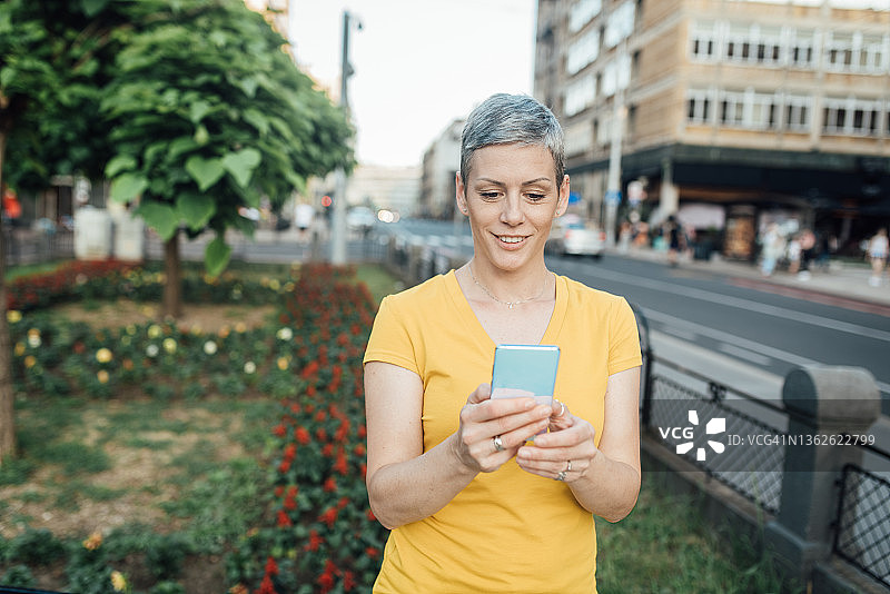 美丽的女人用智能手机游览城市图片素材