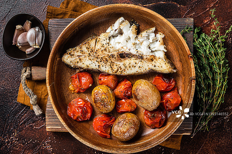 木盘烤比目鱼配烤番茄和土豆。黑暗的背景。俯视图图片素材