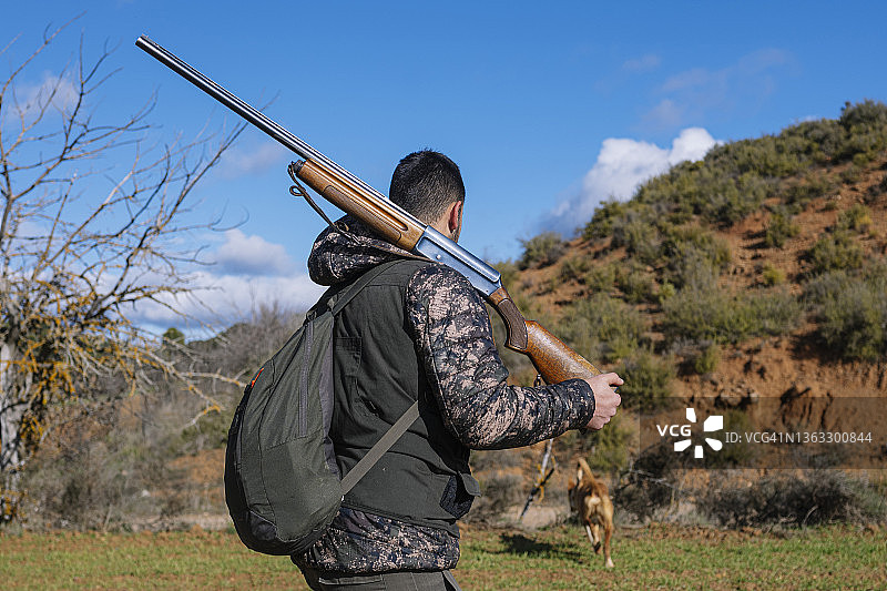猎人扛着猎枪穿过田野。图片素材