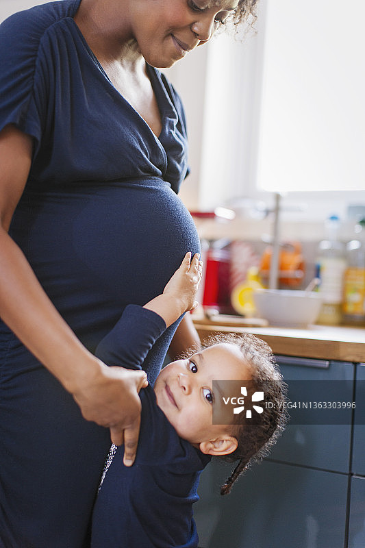 可爱的女儿抚摸孕妇的肚子图片素材