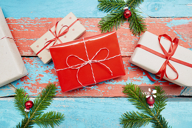 高角度的圣诞礼物和杉木树枝上的绿松石和红色油漆木桌子图片素材