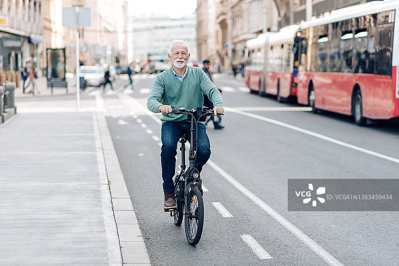 骑自行车穿过城市的老人图片素材