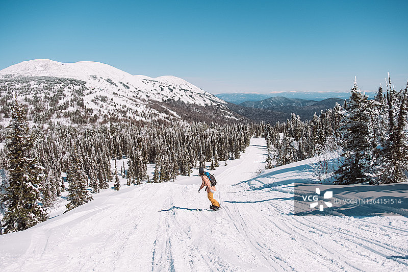年轻的女孩滑雪板与一个滑雪板在自然的山在阳光明媚的天气图片素材