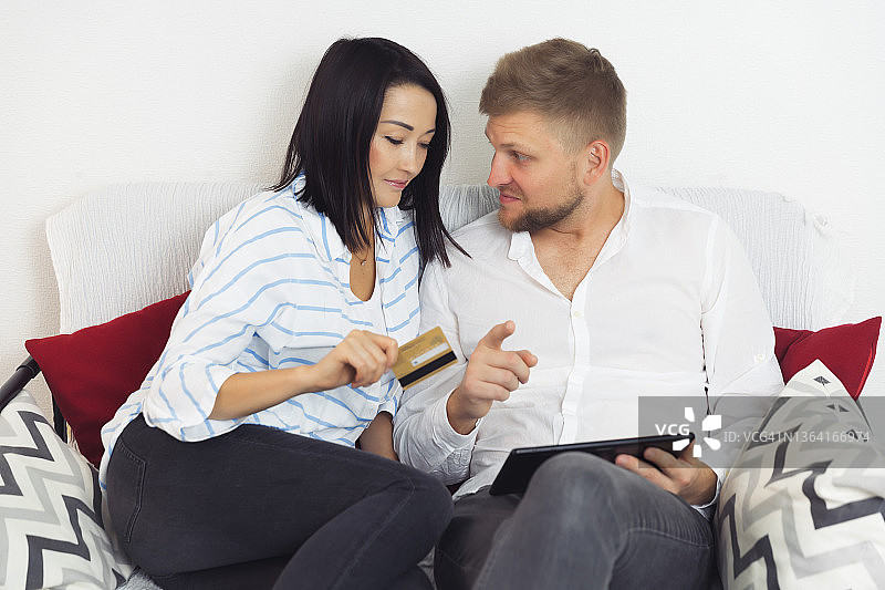 年轻夫妇在家里用金卡支付，用平板电脑上网购物图片素材