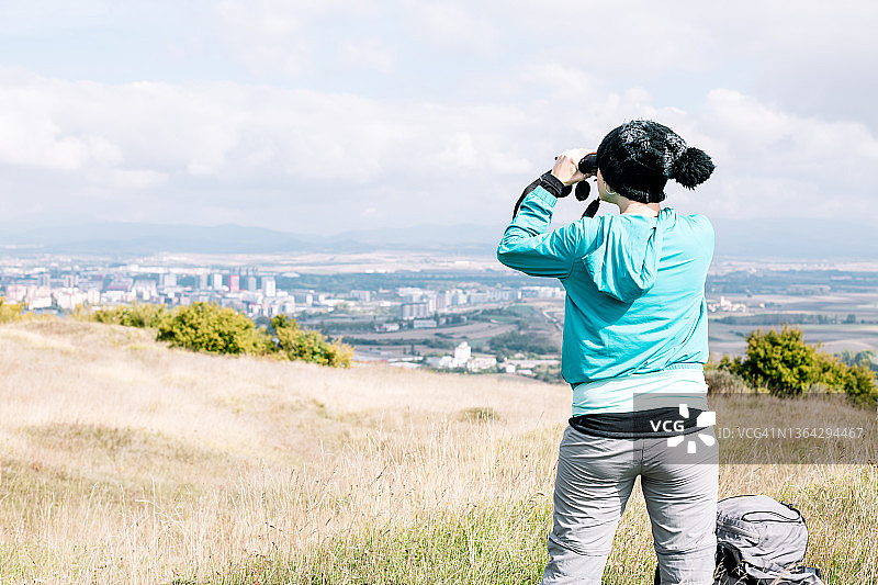 一个不认识的女人在山谷里用双筒望远镜看着地平线图片素材