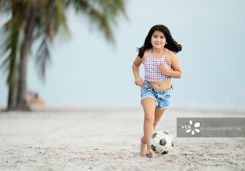 小女孩的腿细节玩足球在海滩上图片素材