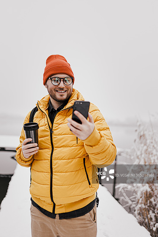 一名男子喝着热咖啡在雪天漫步图片素材