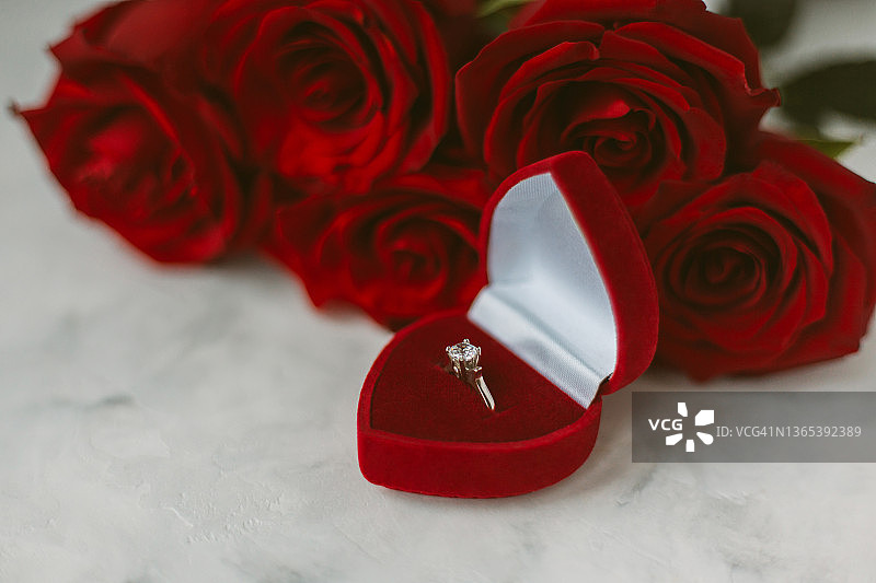 钻石戒指靠近红玫瑰。图片素材
